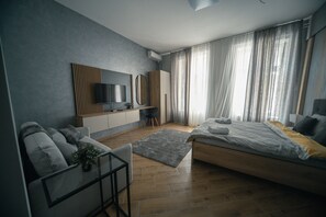 A modern bedroom with a bed, a sofa, a TV, and a desk. - Manoir Apartments (Novi Sad)