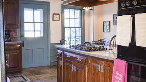 A kitchen with wooden cabinets, a stove, and a window. - Historic Home at Sheldrake in the Finger Lakes. (Ovid)