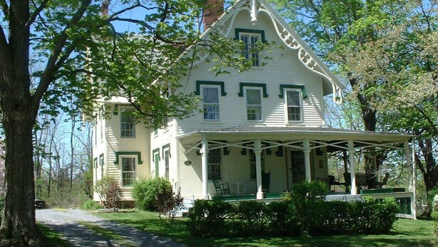 A large, two-story house with a porch and a chimney. - Historic Home at Sheldrake in the Finger Lakes. (Ovid)