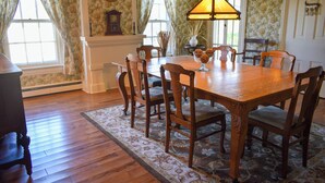 A dining room with a wooden table, six chairs, a chandelier, and floral wallpaper. - Historic Home at Sheldrake in the Finger Lakes. (Ovid)