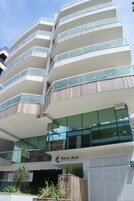 Edifício de vários andares com sacadas, uma placa com o texto 'Porto Azul Residencial' e uma entrada com portão.