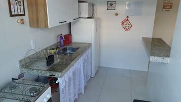 Cozinha compacta com fogão a gás, micro-ondas e pia.