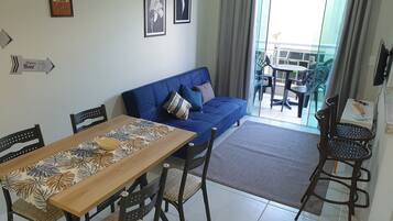 A dining area with a table and chairs, a blue sofa, and a view of the outside.