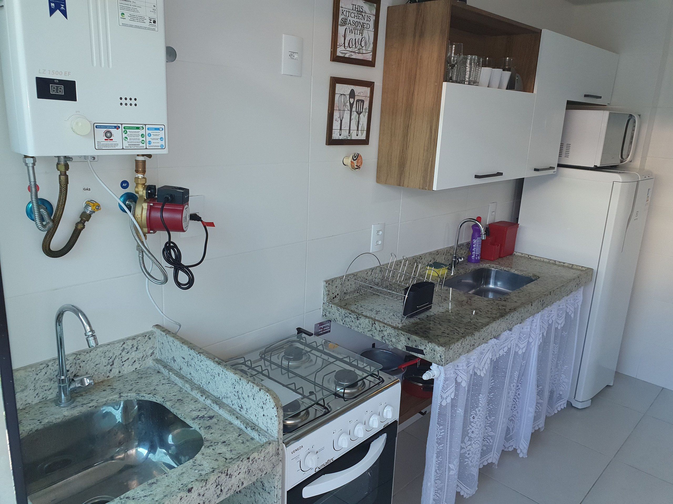 Une cuisine de taille réduite équipée d’une cuisinière à gaz, d’un évier et d’un four à micro-ondes.
