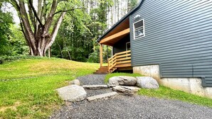 Une cabane dotée d’une terrasse en bois et d’un chemin de pierre menant à l’entrée.
