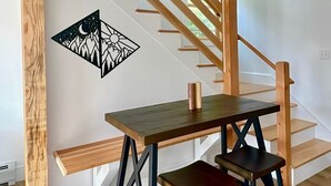 Un escalier avec des marches en bois et une table fixée au mur, accompagnée de deux chaises.