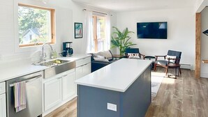 Une cuisine moderne dotée d’un îlot central, de poutres en bois et d’une grande fenêtre.