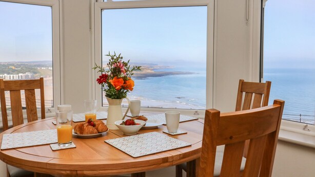 A breakfast table with croissants, fruit, and coffee, overlooking a beach and ocean view. - Apartment 6 Bay View (Scarborough)
