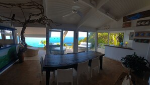 Una habitació àmplia amb un gran taulell de fusta, cadires de vimet i vistes a l'oceà.