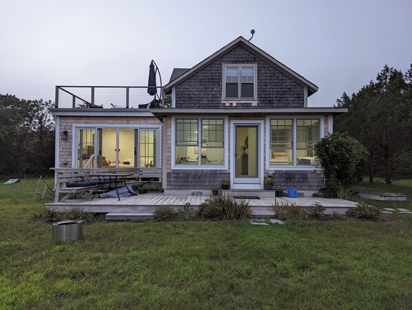 Una casa moderna de dos pisos con ventanas amplias, una terraza y un espacio exterior cubierto.