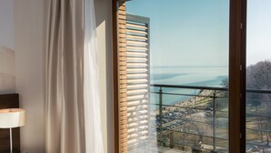 A hotel room with a large window, a bed, a nightstand, and a lamp. - Hotel Różany Gaj - Destigo Hotels (Gdynia)
