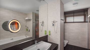 A modern bathroom with a large mirror, a sink, a toilet, and a shower area.