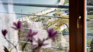 A coastal view with a beach, parked cars, and a pedestrian path. - Hotel Różany Gaj - Destigo Hotels (Gdynia)