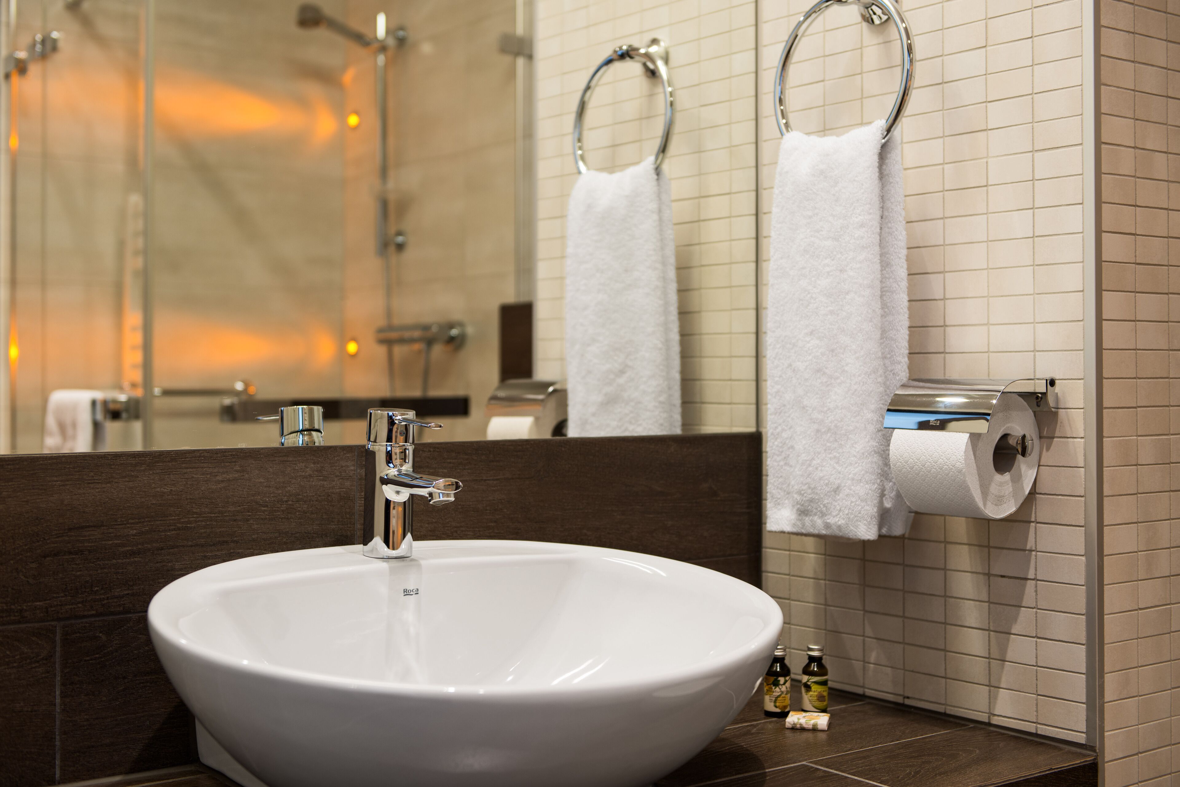 A bathroom with a large white sink, a mirror, and two towel rings.