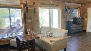 Ett mysigt vardagsrum med en soffa, ett träbord med två vinglas och en takfläkt.
