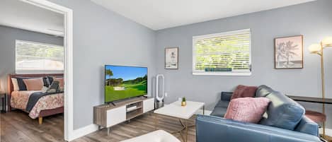 A modern living room with a TV, sofa, and a small table.