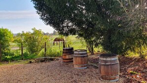 Three wooden barrels in a gravel area with trees and a fence in the background. - Longère Tourangelle (Bréhémont)