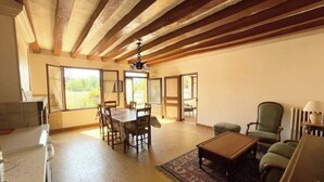 A spacious living area with a dining table, chairs, a coffee table, and a patterned rug. - Longère Tourangelle (Bréhémont)