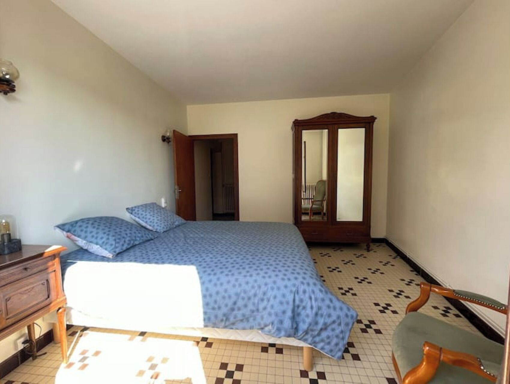 Ein Schlafzimmer mit Bett, Kommode, Stuhl und Kleiderschrank.