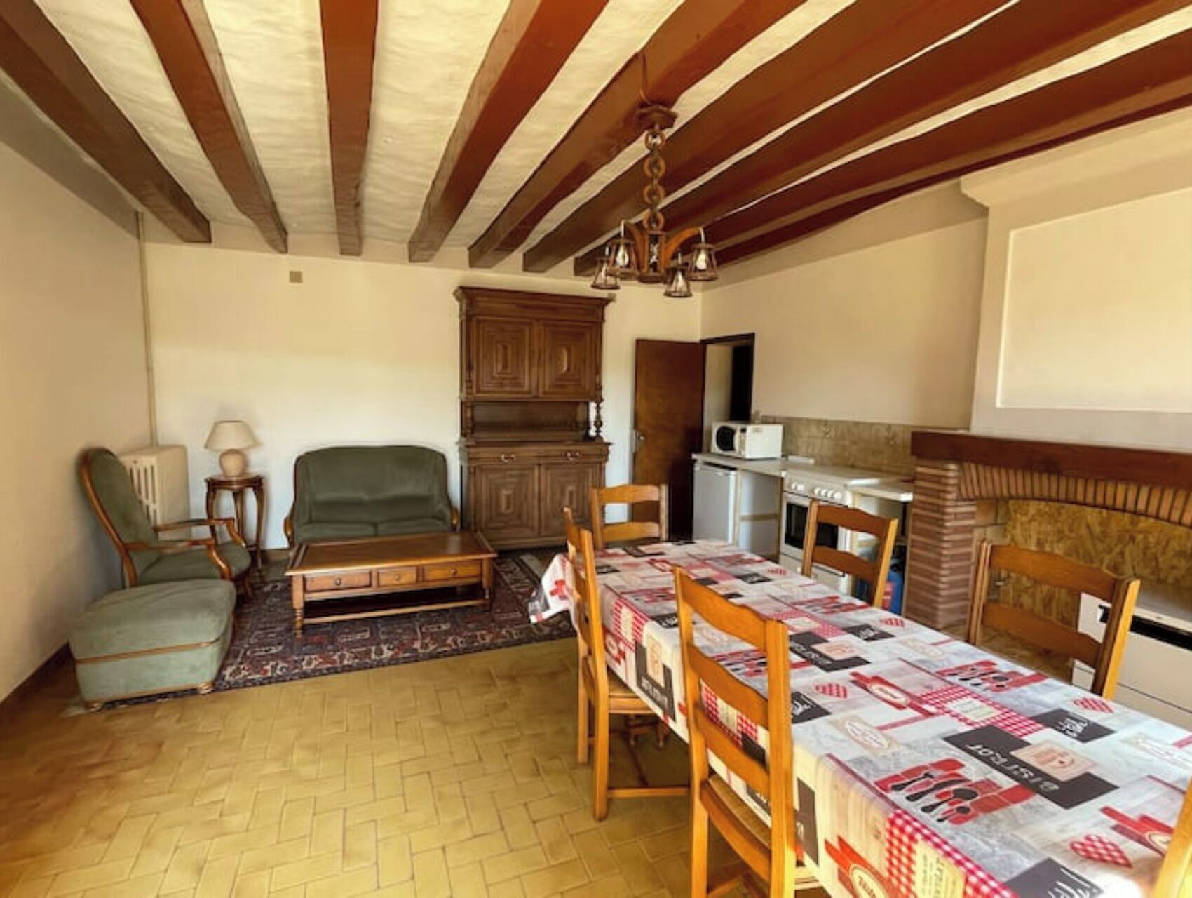 A cozy living room with a fireplace, a dining table set for four, and a kitchen area with a microwave and stove.