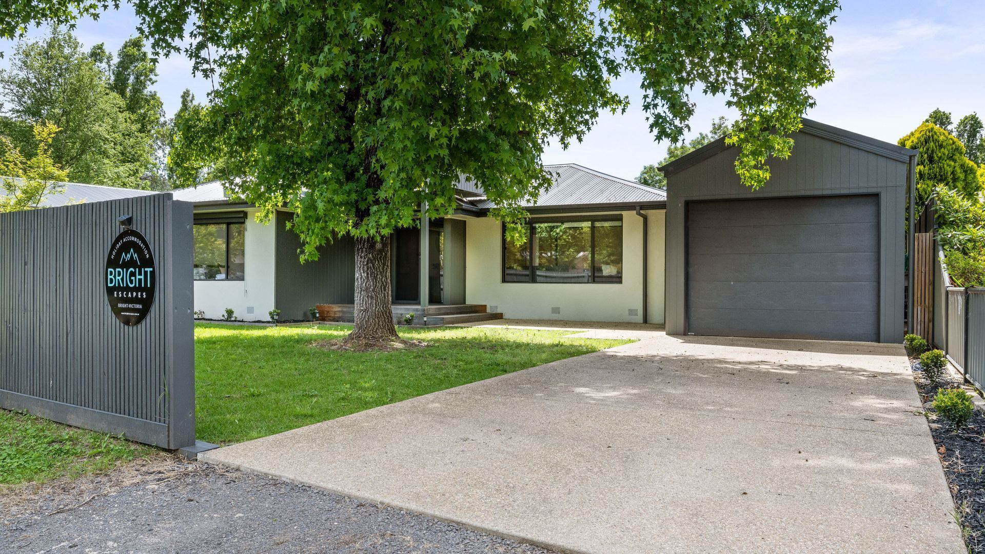 A modern two-story building with a large garage door, a well-maintained lawn, and a sign for BRIGHT ESCAPES.