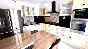 A modern kitchen with a central island, stainless steel appliances, and light wood cabinetry.