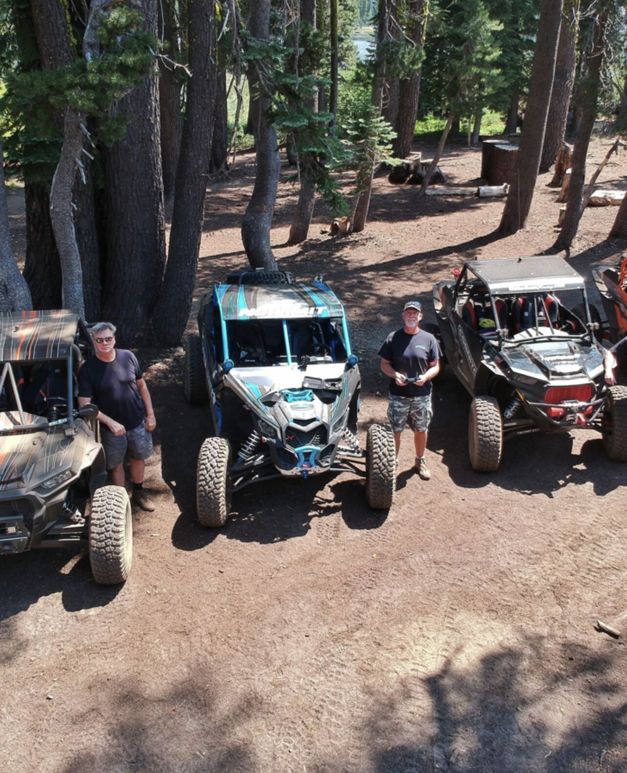 A group of off-road vehicles parked in a forested area.