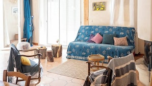 Un vaste salon doté d’un plafond en bois, d’un canapé bleu à motifs, d’une table à manger en bois et d’un sol carrelé avec des motifs hexagonaux.