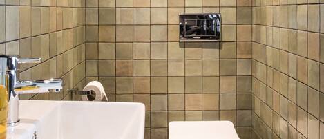 A bathroom with a white bathtub, a toilet, and a small mirror on the wall.