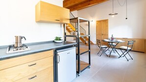 Een moderne keuken met een ingebouwde kookplaat, een kleine koelkast en een eethoek met een tafel en stoelen.