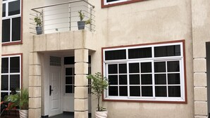 Ein zweigeschossiges Gebäude mit großen Fenstern, einem Balkon und Kübelpflanzen.