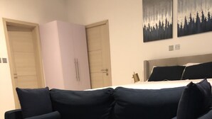 Ein dunkelblaues Sofa in einem Hotelzimmer mit einem Bett, zwei Türen und zwei Bildern an der Wand.