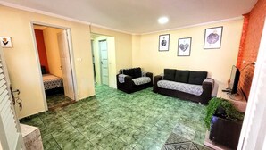 A living room with two sofas, a small bed, and a TV. - House Maraca (Ipojuca)