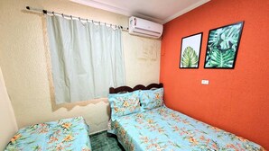 A room with two beds, a window with a curtain, an air conditioning unit, and two framed pictures on the wall. - House Maraca (Ipojuca)