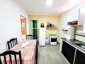 A compact kitchen with a dining table, chairs, a refrigerator, a stove, and a sink. - House Maraca (Ipojuca)