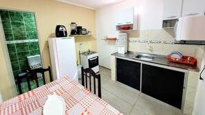 A compact kitchen with a refrigerator, stove, sink, and a dining table with a checkered tablecloth. - House Maraca (Ipojuca)