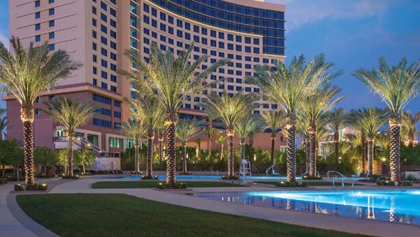 A hotel with a pool area, palm trees, and a large building with many windows. - Margarittaville Las Vegas  (Las Vegas)