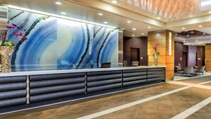 A reception area with a modern design, featuring a large abstract artwork on the wall, a reception desk, and a seating area with chairs. - Margarittaville Las Vegas  (Las Vegas)