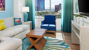 A modern living room with a sofa, armchair, coffee table, and a view of the cityscape through large windows. - Margarittaville Las Vegas  (Las Vegas)