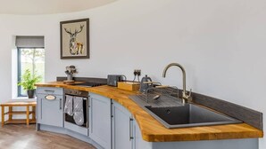 A modern kitchen with a curved island, built-in oven, and a large sink. - Cosy Luxury Lakeside Lodge, surrounded by amazing views and countryside. (Newark)
