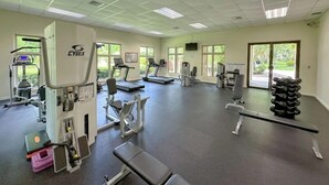 Ein Fitnessraum mit Cardiogeräten, Gewichten und einer Bank.