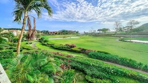 Ein Golfplatz mit gepflegten Rasenflächen, einer Palme und blauem Himmel.