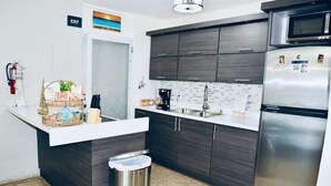 A modern kitchen with dark wood cabinets, a stainless steel refrigerator, and a white countertop.
