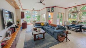 A spacious living room with a sectional sofa, a coffee table, a TV, and a dining area with a table and chairs. - Bella Vista Ocean View Retreat at Los Sueños (Herradura)