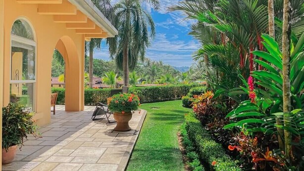 A well-maintained garden with a patio area, palm trees, and a variety of plants. - Bella Vista Ocean View Retreat at Los Sueños (Herradura)