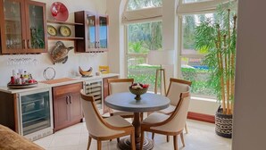 A kitchen with a dining area, featuring a round table with chairs, a refrigerator, cabinets, and a large window with a view of greenery. - Bella Vista Ocean View Retreat at Los Sueños (Herradura)