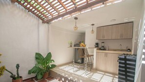 A compact kitchen with a dining area, wooden cabinets, and a small table with chairs. - Private 3 Bedroom Home with Patio in Walled City (Cartagena)