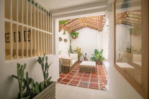A sunlit room with a tiled floor, a wooden bench, a white sofa, and a ceiling fan. - Private 3 Bedroom Home with Patio in Walled City (Cartagena)