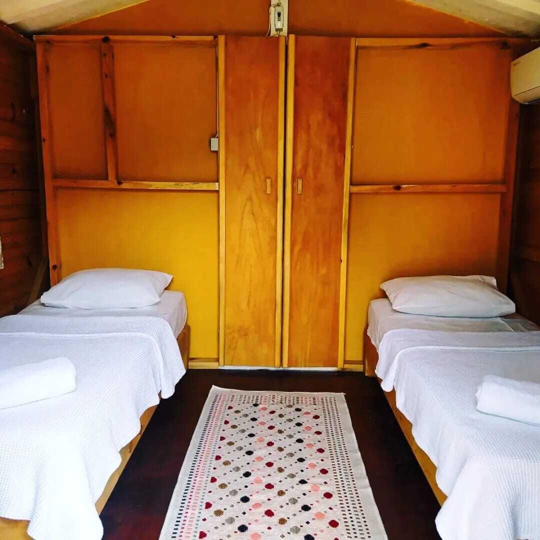 A room with two single beds, wooden walls, and a central wooden panel.
