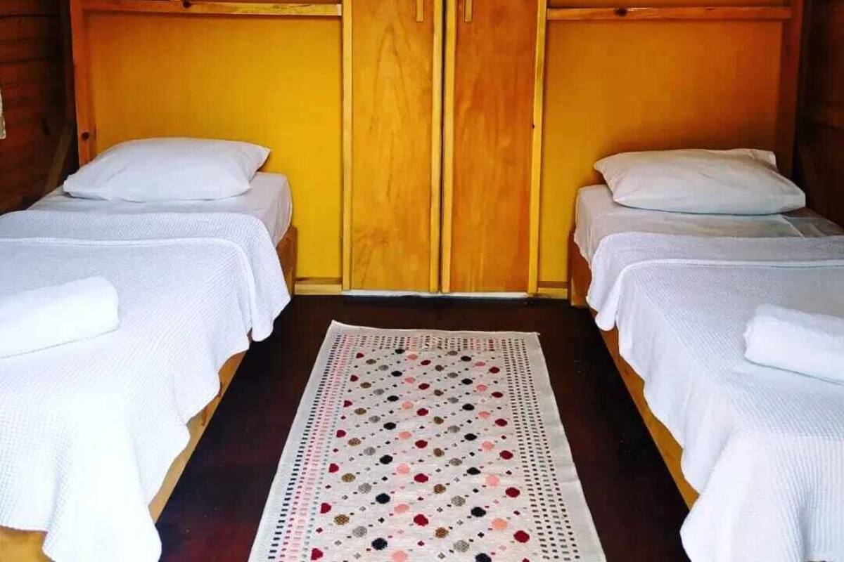 Una habitación con dos camas individuales, paredes de madera y un panel central de madera.